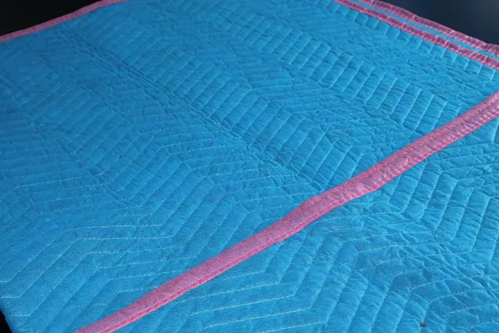 Folded baby blue cotton moving pad with pink trim
