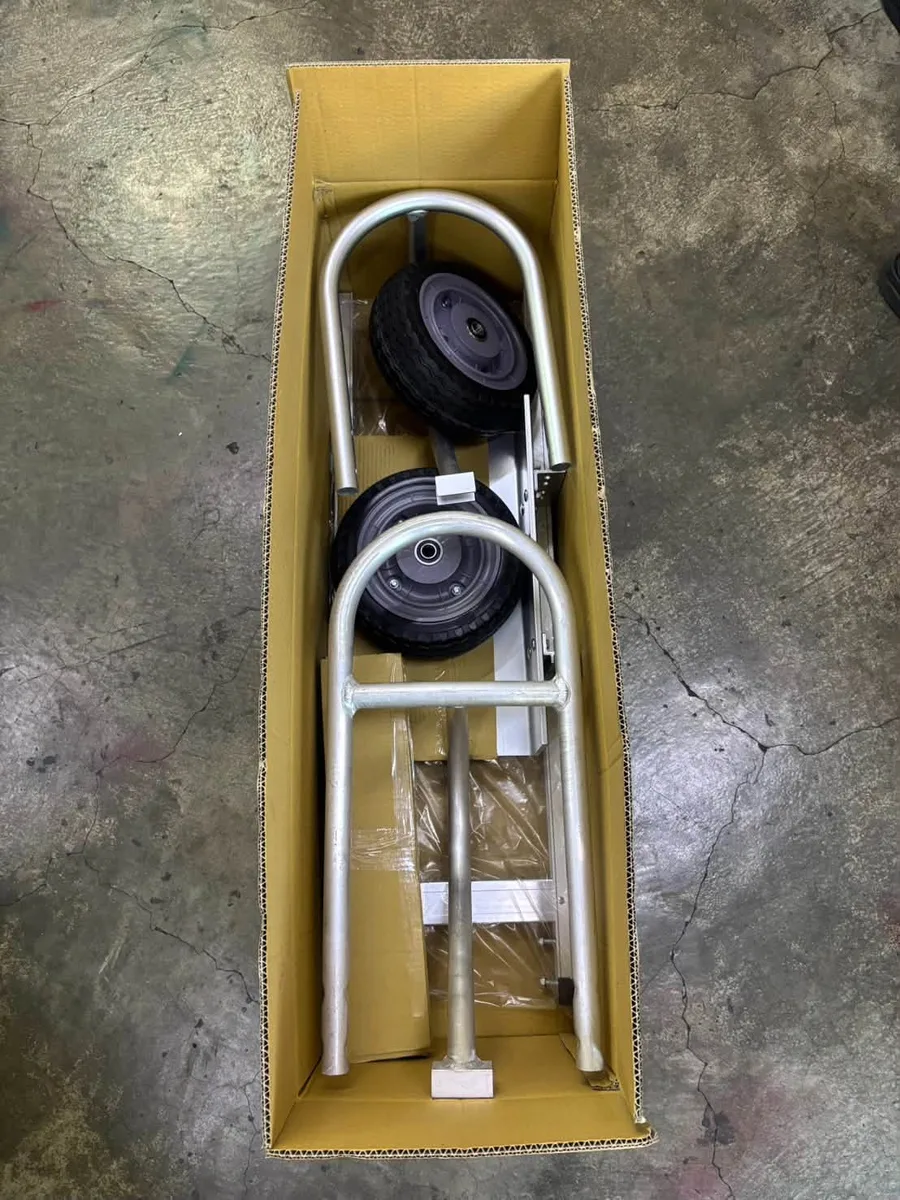 Hand truck packed in a shipping box with wheel and handle parts visible